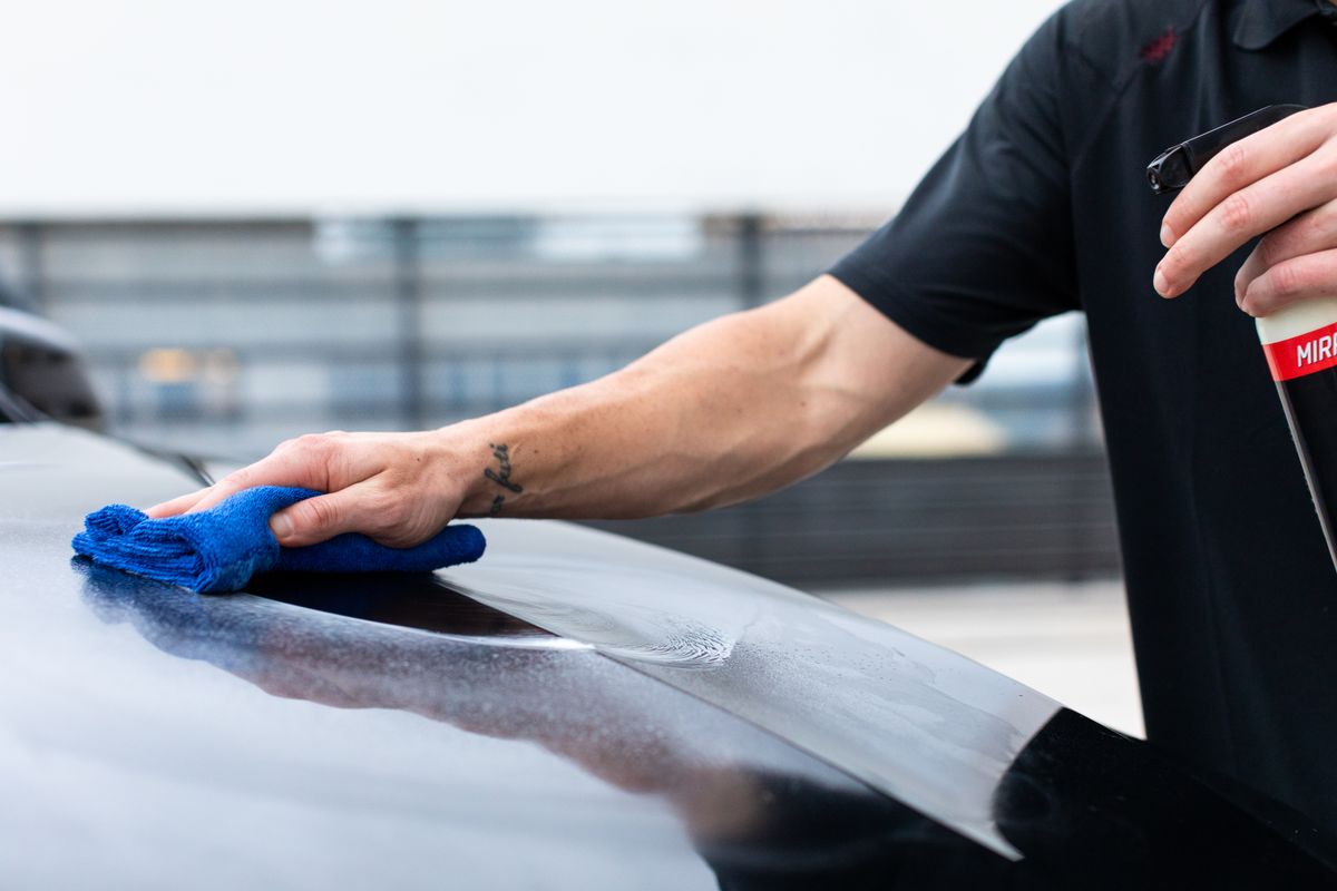Clean car paintwork being carefully finished by hand