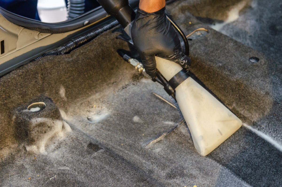 Ground-in dirt being cleaned from a car footwell